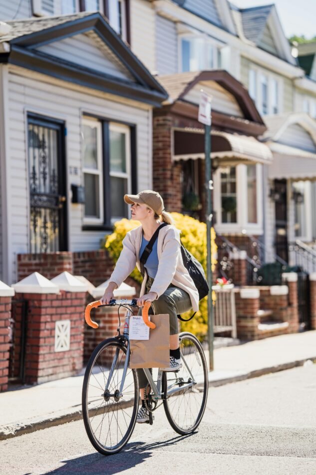 Woman Cyclist with Paper Bag Riding Road in Town